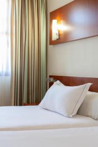 韦尔瓦韦尔瓦理事酒店的一间卧室配有一张带白色床单和镜子的床