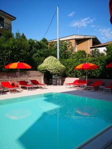 代森扎诺-德尔加达Il Sogno Apartments的一个带红色遮阳伞和椅子的游泳池
