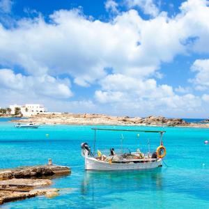 埃斯普霍斯Mar Suites Formentera by Universal Beach Hotels的坐在海滩附近的水中的小船