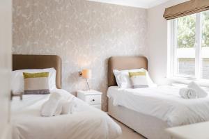 KellingHeathland Lodge - Norfolk Cottage Agency的一间卧室设有两张床和窗户。