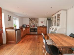 韦茅斯White Horse Cottage的厨房铺有木地板,配有木桌。