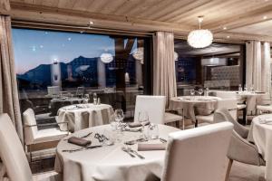 莱热Hôtel Alpina & SPA的餐厅设有白色的桌椅和大窗户