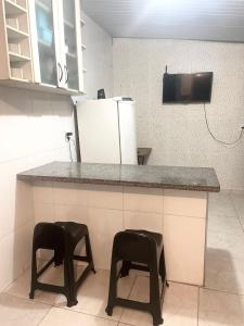 马卡埃Casa top aeroporto的厨房配有冰箱的柜台,设有两张凳子