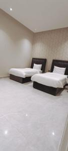 巴哈شاليهات أبيات الفندقية的两张床位于带白色墙壁的房间内