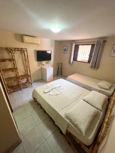 纳塔尔Pousada Recanto de Ponta Negra的一间卧室配有两张床和一台平面电视