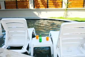 达利安Villa Bianca的游泳池畔的2把椅子和桌子上的饮料