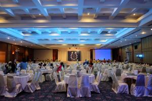 乌汶Ubonburi Hotel的一个带白色桌椅的大型宴会厅