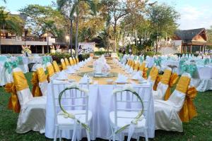 乌汶Ubonburi Hotel的一张桌子,用来举办婚礼,上面摆放着黄白色椅子