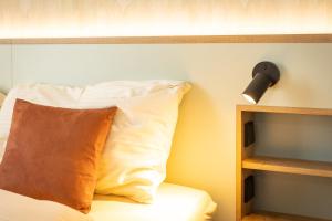 魏森霍恩Hotel zum Löwen的一张带枕头的床和墙上的灯