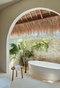 塞隆贝拉纳克Boni Beach Lombok Boutique Hotel的带浴缸和石墙的浴室