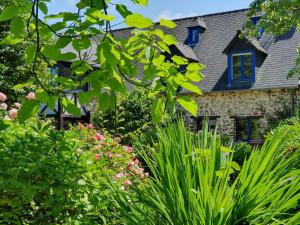 Roz-LandrieuxMaison en pierre dans son nid de verdure的蓝色窗户和植物的石头房子