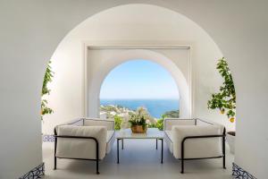 卡普里Palazzo M Capri的客房设有桌子、两把椅子和窗户。