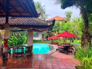 乌布Hotel rooms 2 minutes to Monkey Forest的一个带游泳池、桌子和遮阳伞的度假村