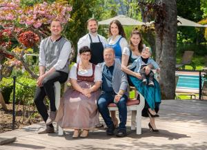 施卢赫湖施卢赫海弗洛拉公园酒店的坐在长凳上拍照的家庭