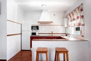 罗切Casa Paqui 3的厨房配有水槽和2张木凳