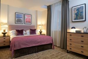 伦敦仕骅廷南肯辛顿酒店公寓的一间卧室配有一张带紫色床单的床和窗户。