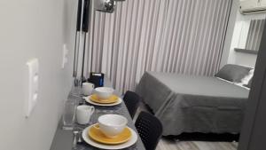 巴西利亚Flats Asa Norte CLN 110 by CentoEdez的一间房间,配有一张桌子、两个杯子和一张床