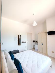 GibaLa Residenza B&B的白色卧室配有白色大床和蓝色枕头