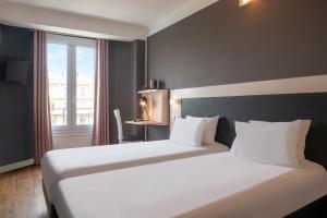 巴黎Hôtel Baldi by Magna Arbor的酒店客房设有两张床和窗户。