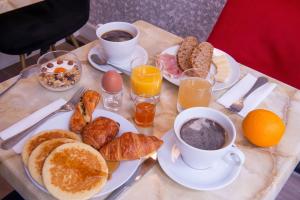 巴黎Hôtel Baldi by Magna Arbor的一张桌子,早餐包括咖啡、鸡蛋和羊角面包