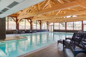 瓦洛西讷勃朗峰多米奥波特斯度假公寓式酒店的一个带椅子和木制天花板的大型游泳池