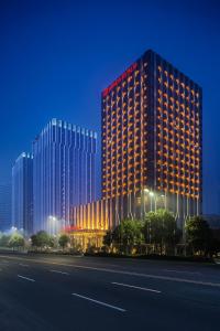 蚌埠蚌埠富力万达嘉华酒店的一座高大的建筑,旁边灯火通明