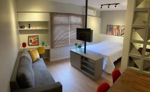 巴西利亚Flat Condomínio Garden Park by CentoEdez的一间卧室配有一张床、一张沙发和一台电视。