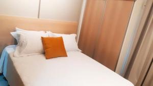 巴西利亚Flat Asa Sul Condomínio Golden Place by CentoeDez的床上有一个橙色枕头