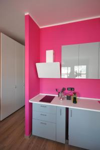 热那亚H2Ome Ponte Morosini的厨房设有粉红色的墙壁和白色的橱柜。