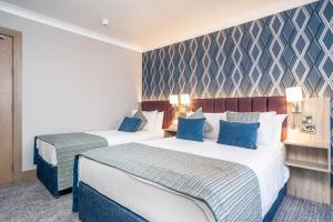 邓莱里Rochestown Lodge Hotel的两张位于酒店客房的床,配有蓝色枕头