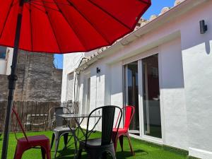 马拉加Malaga City Suites的一张桌子和椅子,配有红色雨伞