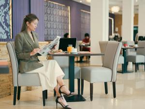 诺阿瑟Sky Casa Airport的坐在桌子旁读报纸的女人