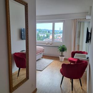 克罗伊茨林根Sonniges 1-Zimmerappartement mit Blick über Kreuzlingen的客厅里的镜子,配有红色的椅子和一张桌子