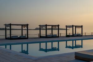 圣玛丽亚Ambassador Luxury Villas的水边带椅子的游泳池