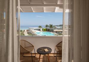 奥马斯帕纳吉亚斯Antigoni Seaside Resort的阳台享有游泳池和海洋的景致。