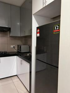 吉隆坡Zetapark, The Loft的厨房配有白色橱柜和黑色冰箱。