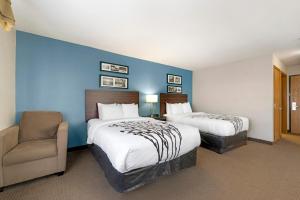 海斯Sleep Inn & Suites Hays I-70的酒店客房,配有两张床和椅子