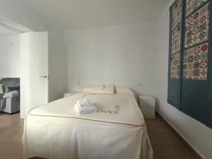 麦地那西多尼亚El barrio的白色卧室配有一张带白色床单的大床