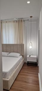 地拉那Heart of Tirana Apartment的卧室配有白色大床和灯
