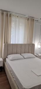 地拉那Heart of Tirana Apartment的卧室内一张白色大床和白色窗帘