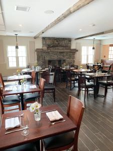 查尔斯敦The General Stanton Inn的餐厅设有木桌、椅子和壁炉