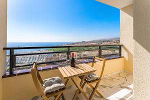帕莱索海滩Prime apartments Club Paraiso Ocean view的阳台配有桌椅和一瓶葡萄酒
