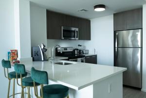 迈阿密Luxury 2'2 apartment brickell downtown的厨房配有白色的柜台和绿色的椅子