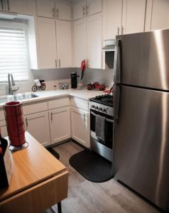 奥马哈1 Bedroom Stylish Oasis的厨房配有不锈钢冰箱和白色橱柜
