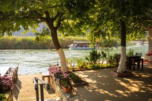穆拉Aktaş Butik Hotel的一条河上种满了树木、桌子和长凳的船