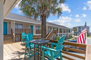 橡树岛The Beach House at Oak Island by Carolina Resorts的棕榈树甲板上的桌椅