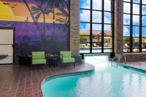 格林伍德SureStay Plus Hotel by Best Western Greenwood的酒店大堂设有1个带椅子和桌子的游泳池