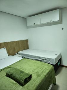 巴纳内拉斯Apt 202 e 203 no ZUPPOLINI GARDEN HOTEL Bananeiras PB的小客房内的两张床,配有绿色床单