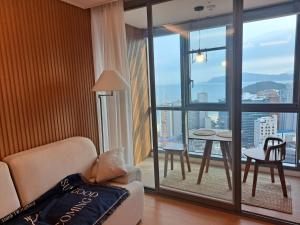 釜山premium ocean view in HAEHUNDAE BONA TRAVEL的带沙发和大窗户的客厅
