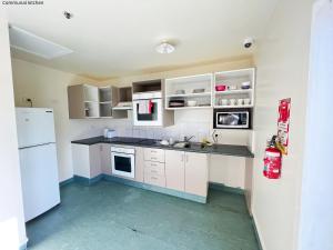 罗托鲁瓦Stay Hostel Rotorua的厨房配有白色橱柜和白色冰箱。
